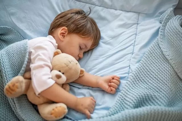 Schlafendes Baby mit Teddy im Arm