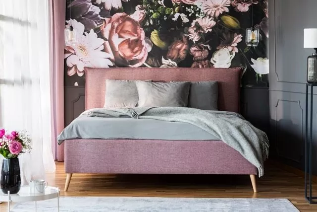 Schlafzimmer mit pinkem Polsterbett und Blumentapete